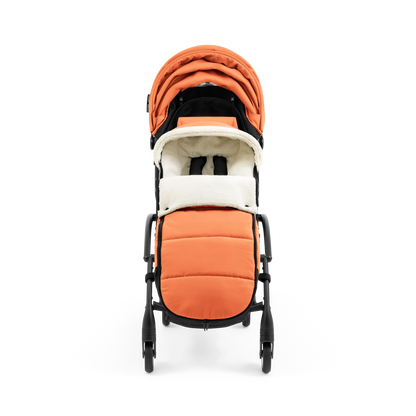 A stroller with a orange colored padded footmuff, cream fleece lining, and a black frame, shown from the front on a white background.