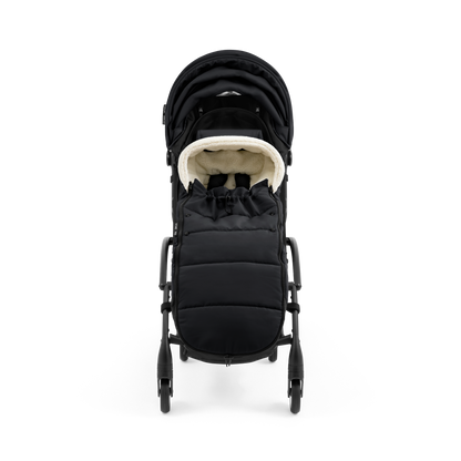A stroller with a black colored padded footmuff, cream fleece lining, and a black frame, shown from the front on a white background.