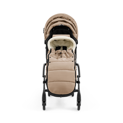 A stroller with a beige colored padded footmuff, cream fleece lining, and a black frame, shown from the front on a white background.