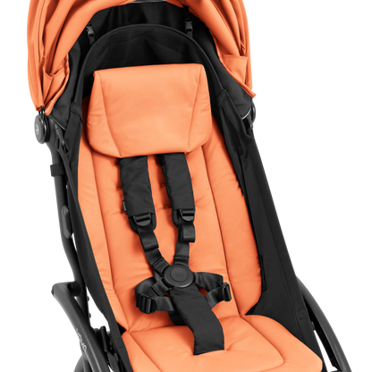 A compact yoyo 5 stroller with a peach orange canopy and seat lining, a black frame, and black wheels, shown on a plain white background.