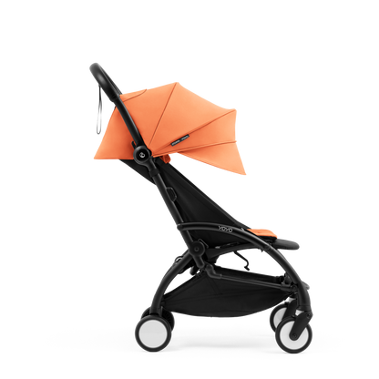 A compact yoyo 5 stroller with a peach orange canopy and seat lining, a black frame, and black wheels, shown on a plain white background.