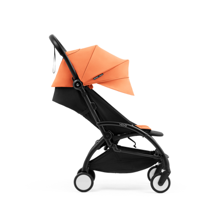 A compact yoyo 5 stroller with a peach orange canopy and seat lining, a black frame, and black wheels, shown on a plain white background.