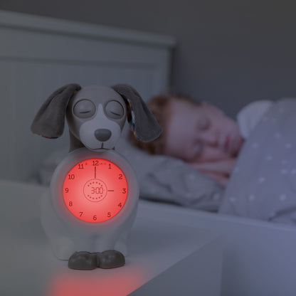 A beige and white dog with a clock in its colour changing belly, while a toddler sleeps in their bed.