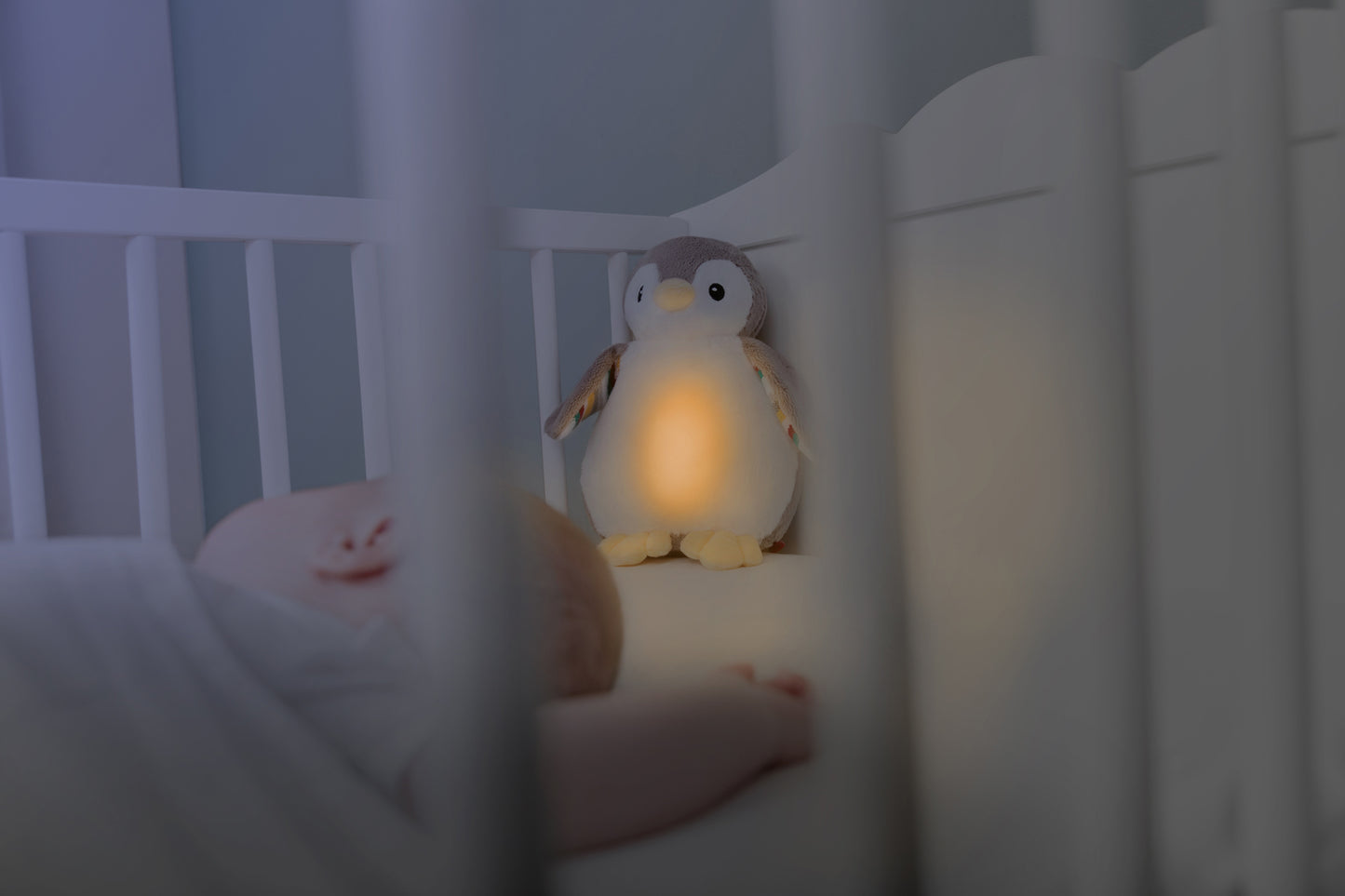 A beige and white bird with night light and soothing sounds, while baby sleeps in their cot.